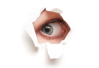 Person's eye peeping through hole