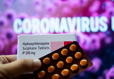 Photograph of hydroxychloroquine sulphate tables in a white coloured box in front of a red coloured board with coronavirus outbreak mentioned