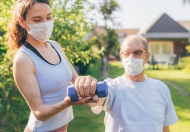 A physiotherapist helps an old man exercise