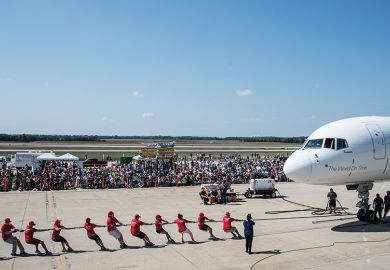 People pull plane on runway