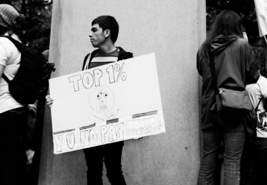 Portland, Oregon, USA - October 6, 2011 A young man holds a sign that reads Top 1٪ Y U No Pay Taxes during an Occupy Wall Street event in downtown Portland. Portland, Oregon, USA - October 6, 2011 A young man holds a sign that reads Top 1٪ Y U No Pay Taxes during an Occupy Wall Street event in downtown Portland.