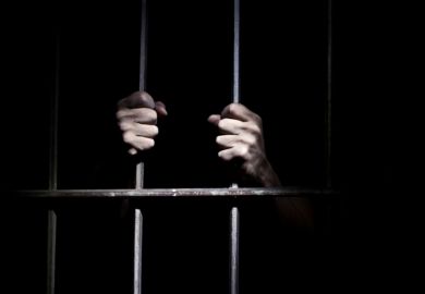A prisoner behind bars A prisoner holding the bars of a cell