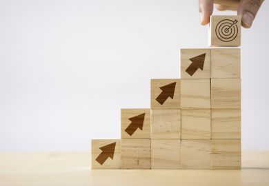 Wooden bricks with arrows pointing upwards towards a target, symbolising promotion