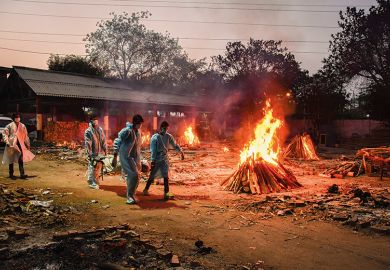 Workers carry the body of a person who has died of Covid-19 as funeral pyres burn during a mass cremation at a crematorium, New Delhi, 2021/05/03   Workers carry the body of a person who has died of Covid-19 as funeral pyres burn during a mass cremation at a crematorium, New Delhi, 2021/05/03