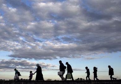 Refugees walking across a field Refugees walking across a field