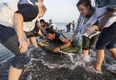 Kos, Greece - October 2015: Volunteers give a hand to migrants from Afghanistan who arrived at Kos from Turkey on a dinghy Kos, Greece - October 2015: Volunteers give a hand to migrants from Afghanistan who arrived at Kos from Turkey on a dinghy