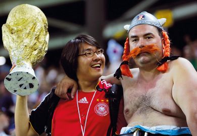 A South Korean supporter (L) holds a miniature replica of the World Cup trophy to illustrate Overseas drive ‘puts HE quality at risk’