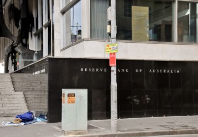 Reserve Bank of Australia name on black granite wall in Sydney Australia with a homeless man sleeping nearby