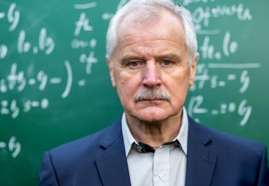 A glum old professor in front of a blackboard