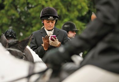 A woman on a horse uses a mobile phone
