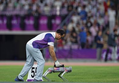A referee puts a discus onto a robot dog at an athletics meeting