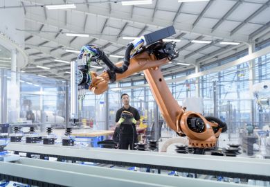 An engineer programmes a robot in a robotics research facility, illustrating regional growth An engineer programmes a robot in a robotics research facility, illustrating regional growth