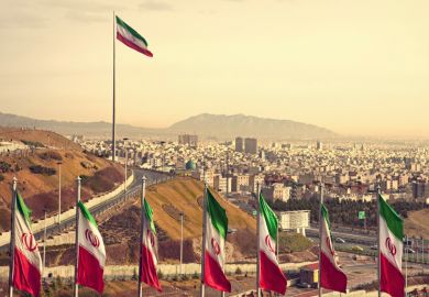 Row of Iran flags against Tehran skyline Row of Iran flags against Tehran skyline