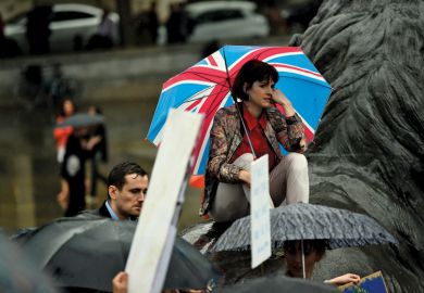 Sad woman with Union flag umbrella in rain at Trafalgar Square