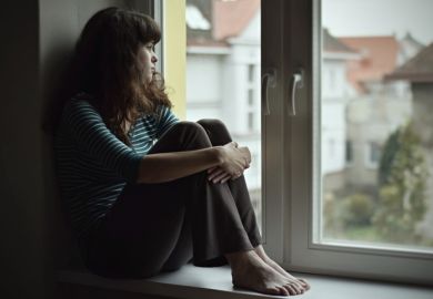 Sad young woman sitting on the window at home isolated, watching out. Coronavirus quarantine concept.