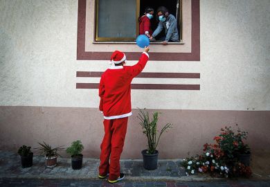 Man dressed as Santa passes a balloon to people through a window