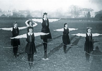 schoolgirls balancing a ball and plate on their heads while spinning a hoop
