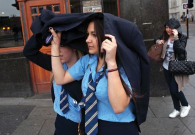 Schoolgirls shelter heads from rain, Liverpool