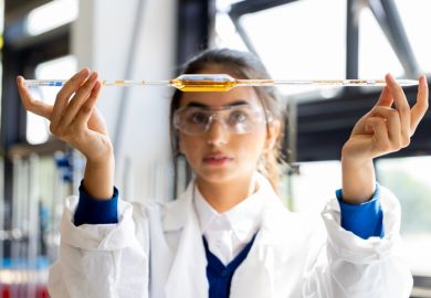 An Asian student holds a pipette level, symbolising equlaity in international collaboration 