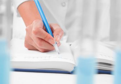 Scientist writing in notebook in laboratory