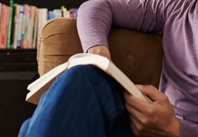 Seated man on sofa reading book