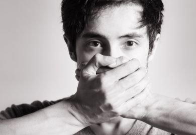 A man with his hands over his mouth, symbolising self-censorship