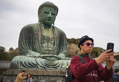 Man taking a selfie in front of a Buddha