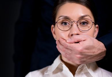 A man puts his hand over a woman's mouth