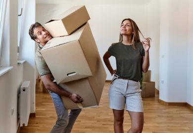 A man carries heavy boxes while a woman looks on