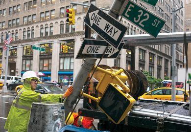 A private contractor replaces a traffic signpost with a newer version in New York City, illustrating change of direction in America