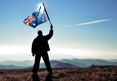 Silhouette of man waving Australian flag on hilltop