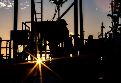 Silhouette of people working on oil rig at sunset Silhouette of people working on oil rig at sunset