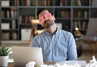 A business person sleeps with post-it notes of open eyes on his eyes A business person sleeps with post-it notes of open eyes on his eyes