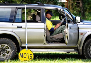 A road-worker takes a break with a slow sign in Australia, to illustrate university administrators deliberately dragging out research fraud investigations to avoid external scrutiny.