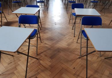 Small white exams desks in a hall