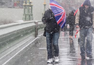 Man crosses bridge with Union Jack umbrella as snow falls