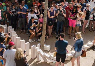 Spectators watch large domino pieces collapse