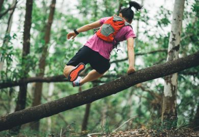 Sportswoman cross country trail running in forest