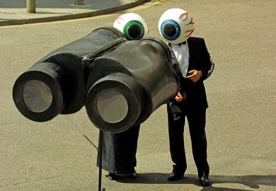 People dressed as eyeballs watch through giant pair of binoculars