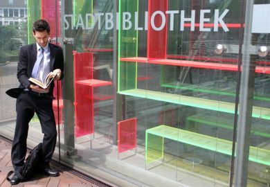 A suited man reads a book outside an empty bookshop