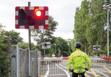A cyclist stops at a red light at a level crossing A cyclist stops at a red light at a level crossing to illustrate PhD enrolment hangs on an email