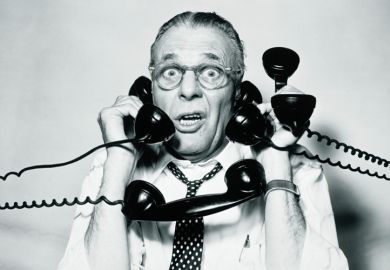 Stressed businessman answering four telephones