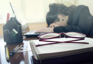 Stressed woman with head on desk