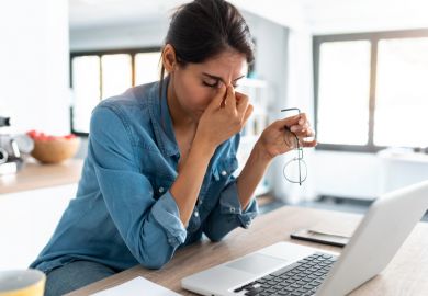stressed woman working from home on laptop looking worried, tired and overwhelmed