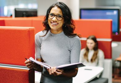 Student with book in Leeds University library