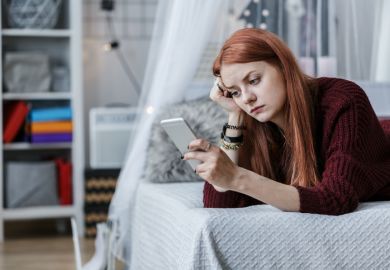 A student looking at her mobile phone A student looking at her mobile phone