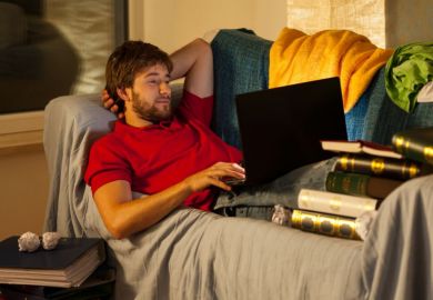 Student on laptop surrounded by books
