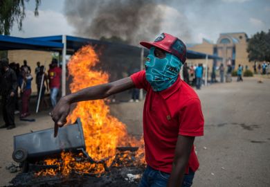 Students shout slogans next to a burning barricade during clashes with South African anti-riot police and campus security at a demonstration in support of the Fees Must Fall movement in 2016