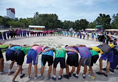 Students in linked circle on beach