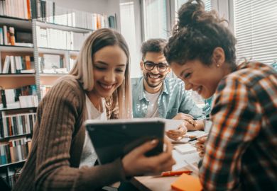 A group of students look at a tablet A group of students look at a tablet